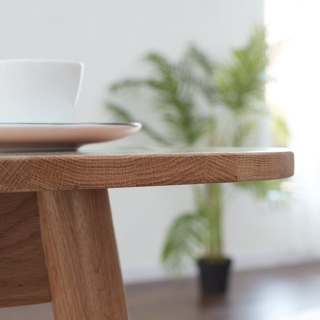 Wooden table with a blurred background of plants and a white wall