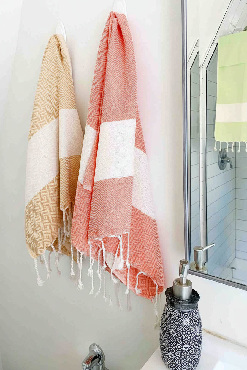 Eco-friendly Turkish tea towels in mustard, orange, and lime green hanging in a modern bathroom.
