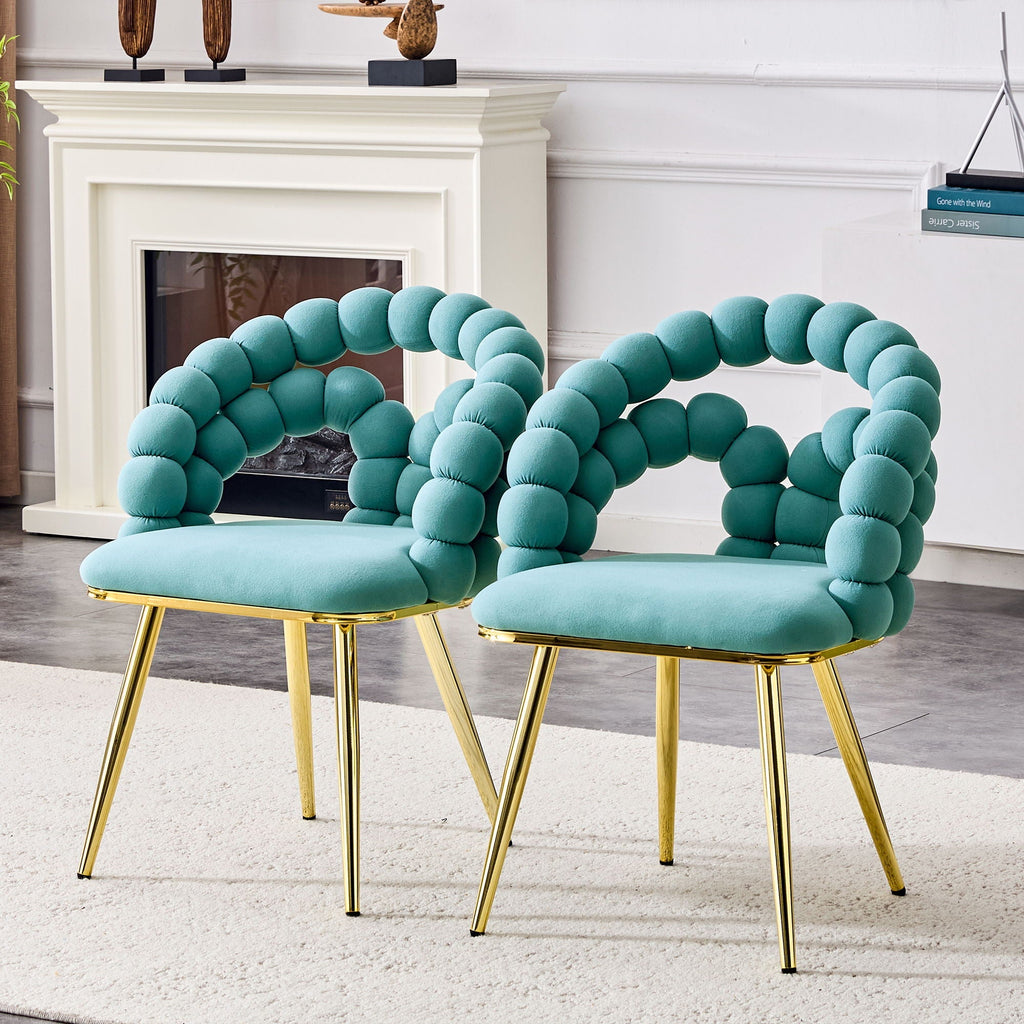 Two teal chairs with gold legs in a living room setting.