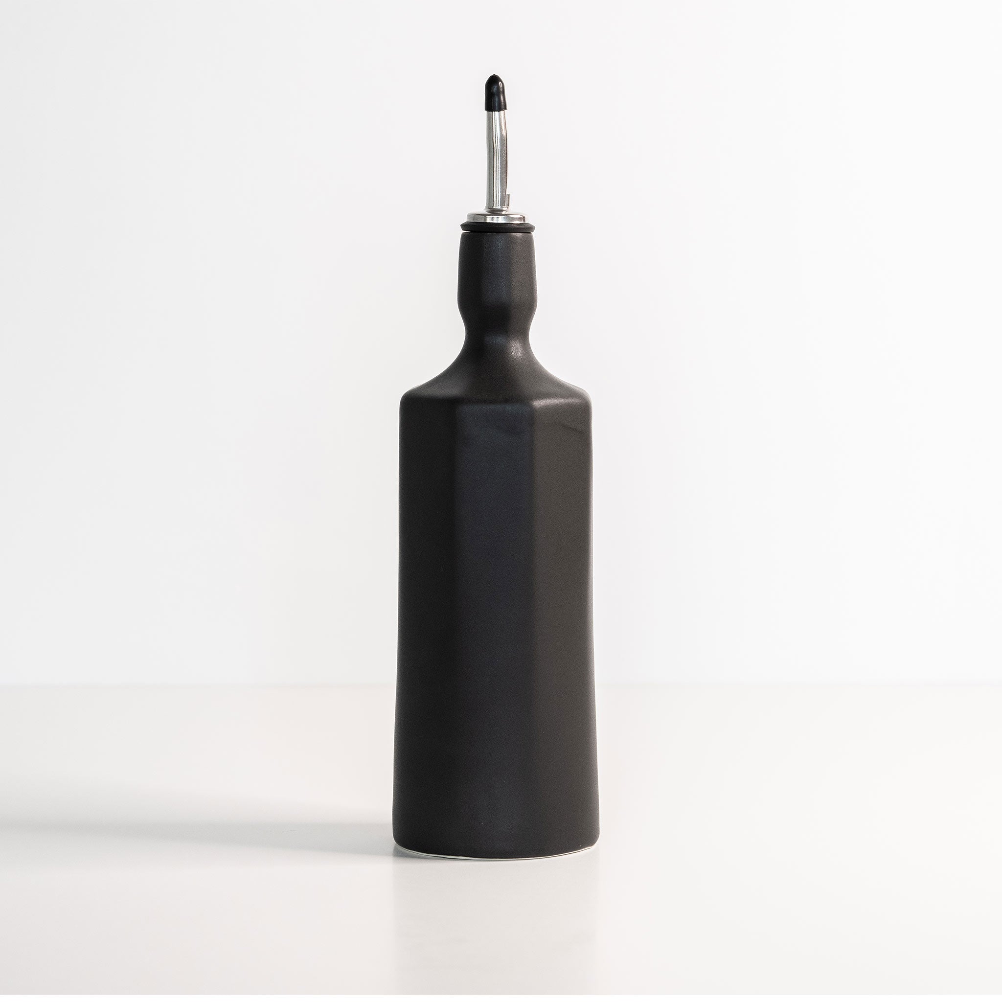 Black oil bottle with a metallic nozzle on a white background