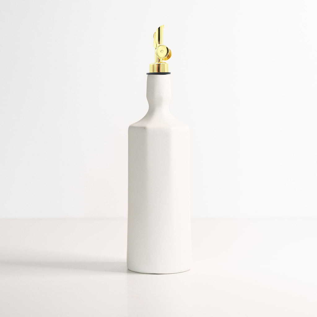 White ceramic bottle with a gold nozzle on a light gray background