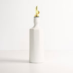 White ceramic bottle with a gold nozzle on a light gray background