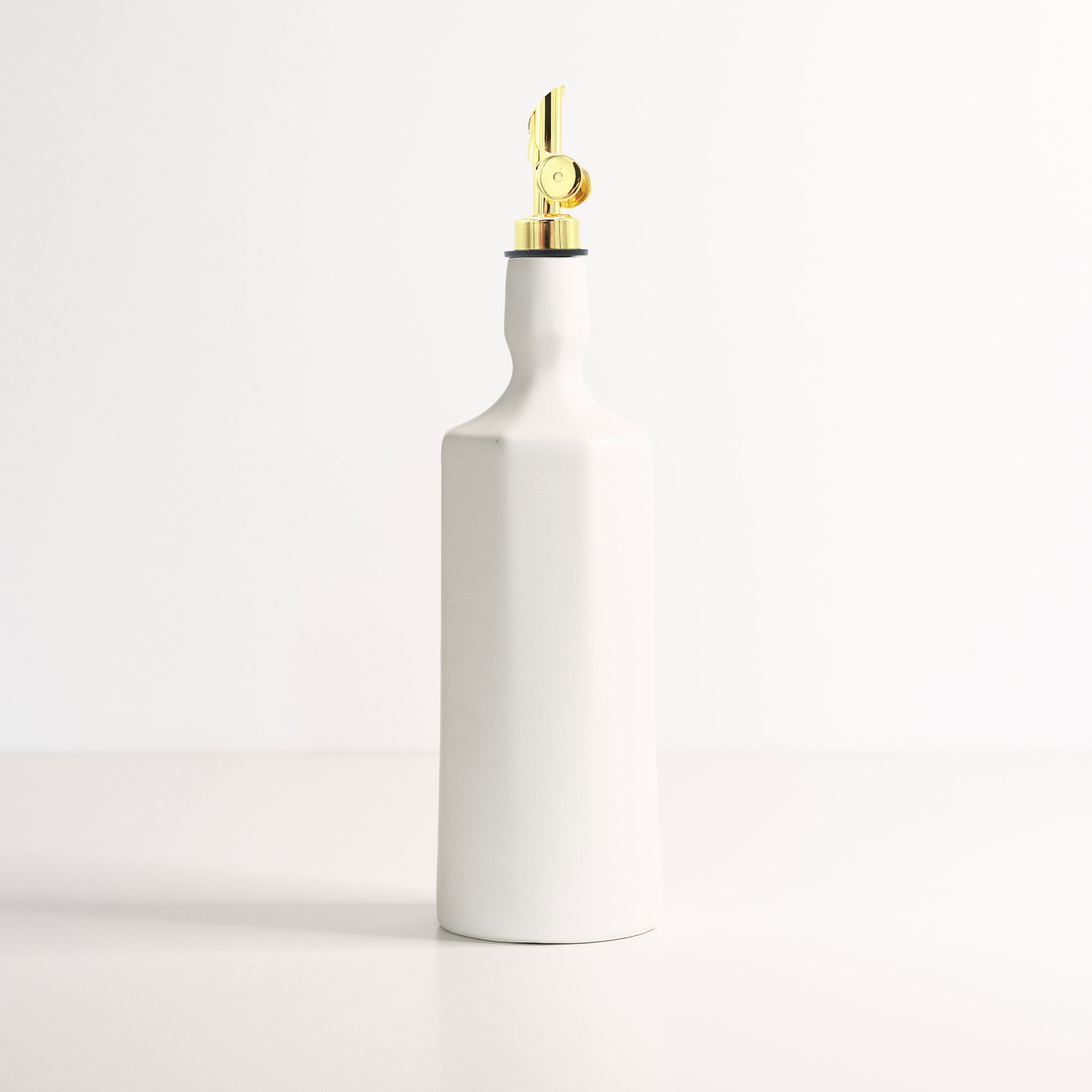 White ceramic bottle with a gold nozzle on a light gray background