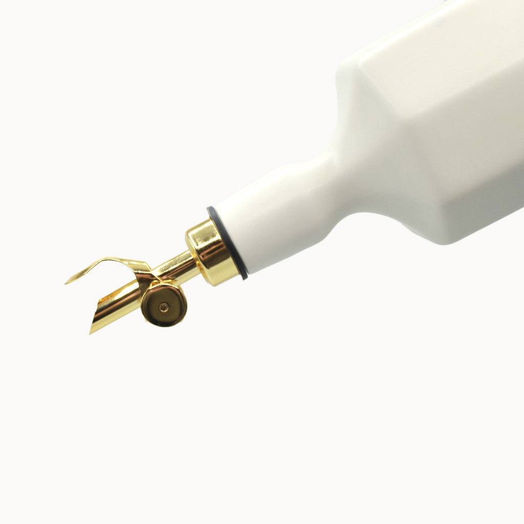 Close-up of a white dental tool with a gold nozzle on a white background