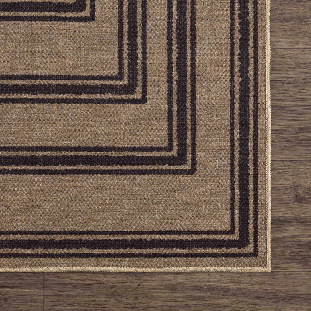 Close-up of a brown rug with black geometric patterns on a wooden floor.