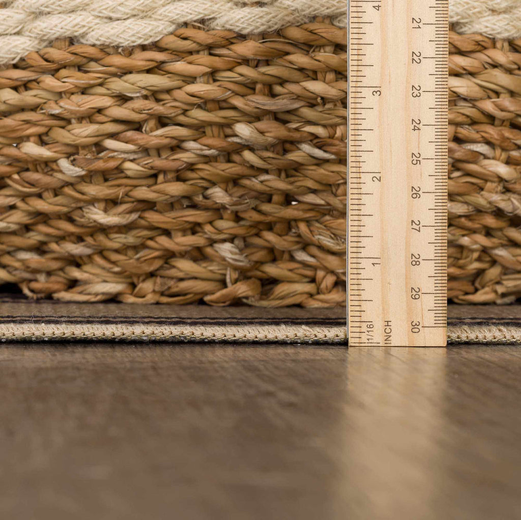 Close-up of a woven mat with a ruler for scale on a reflective surface.