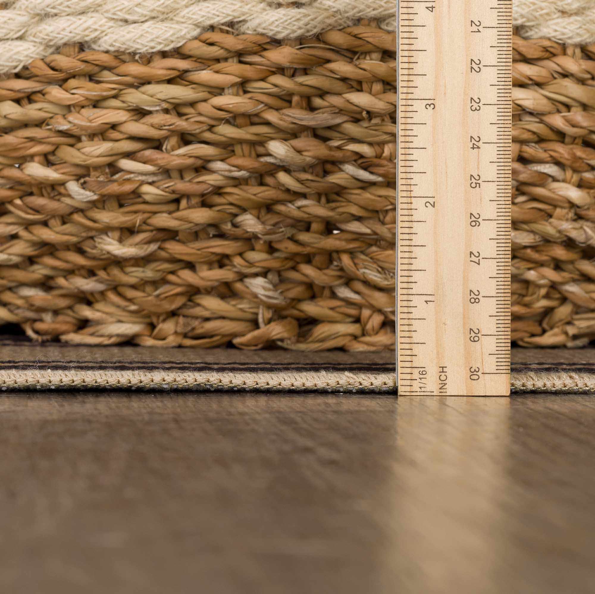 Close-up of a woven mat with a ruler for scale on a reflective surface.