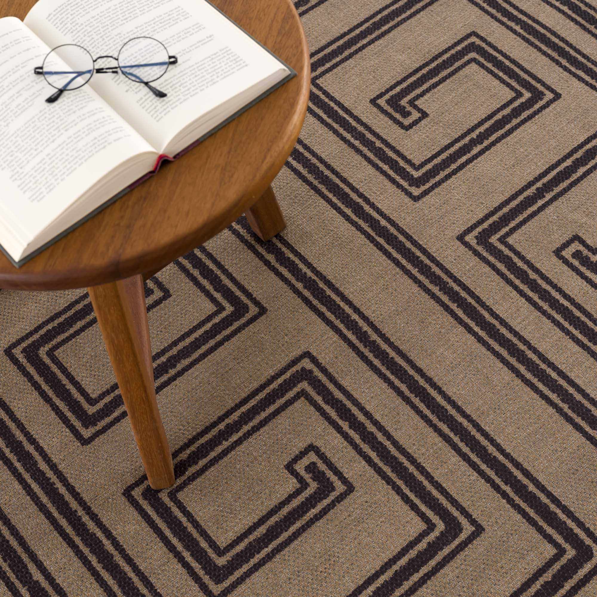 Book with glasses on a wooden stool on a patterned carpet