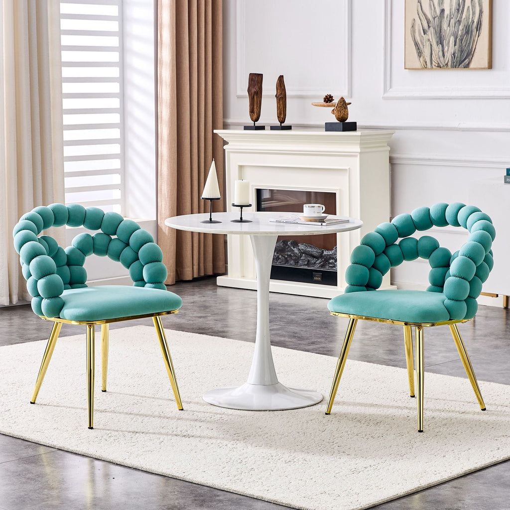 Two turquoise chairs with gold legs in a living room setting.