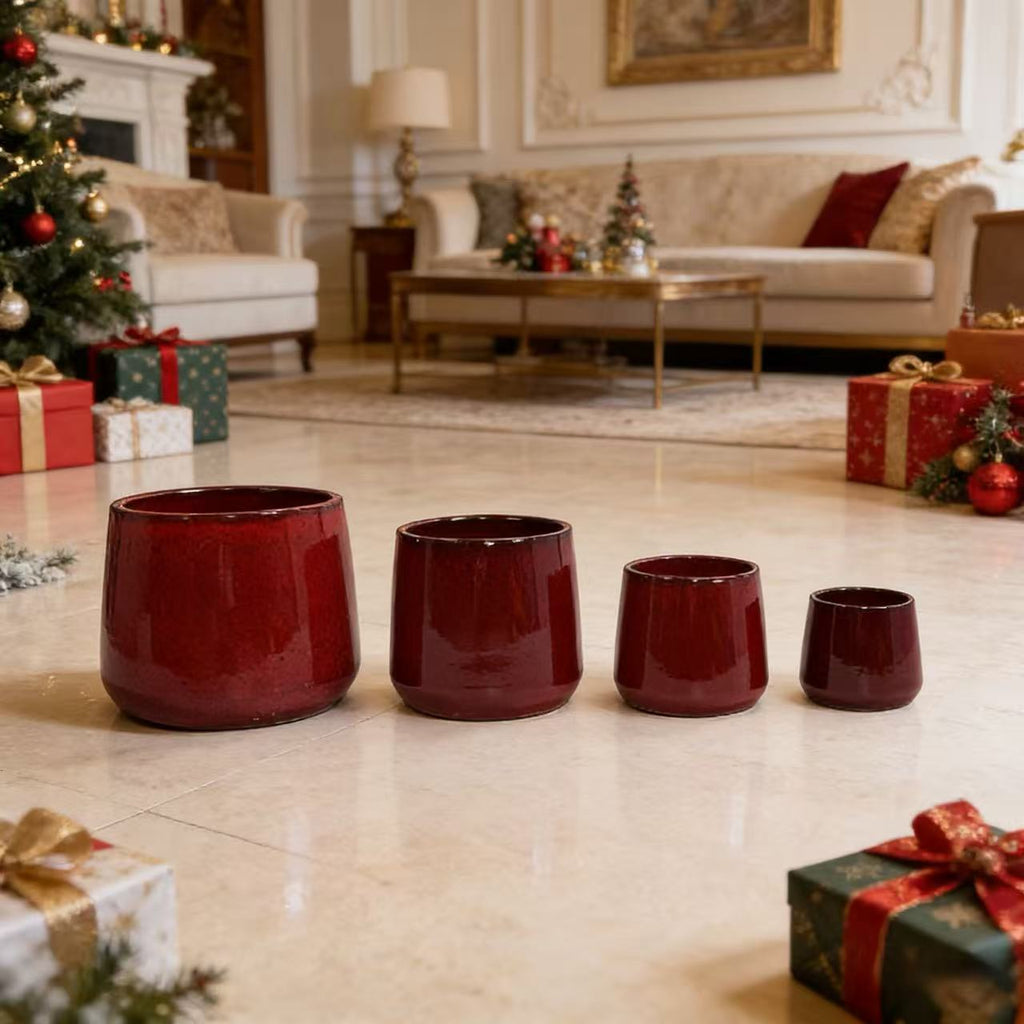 Four red ceramic pots on a tiled floor with Christmas decorations in the background.