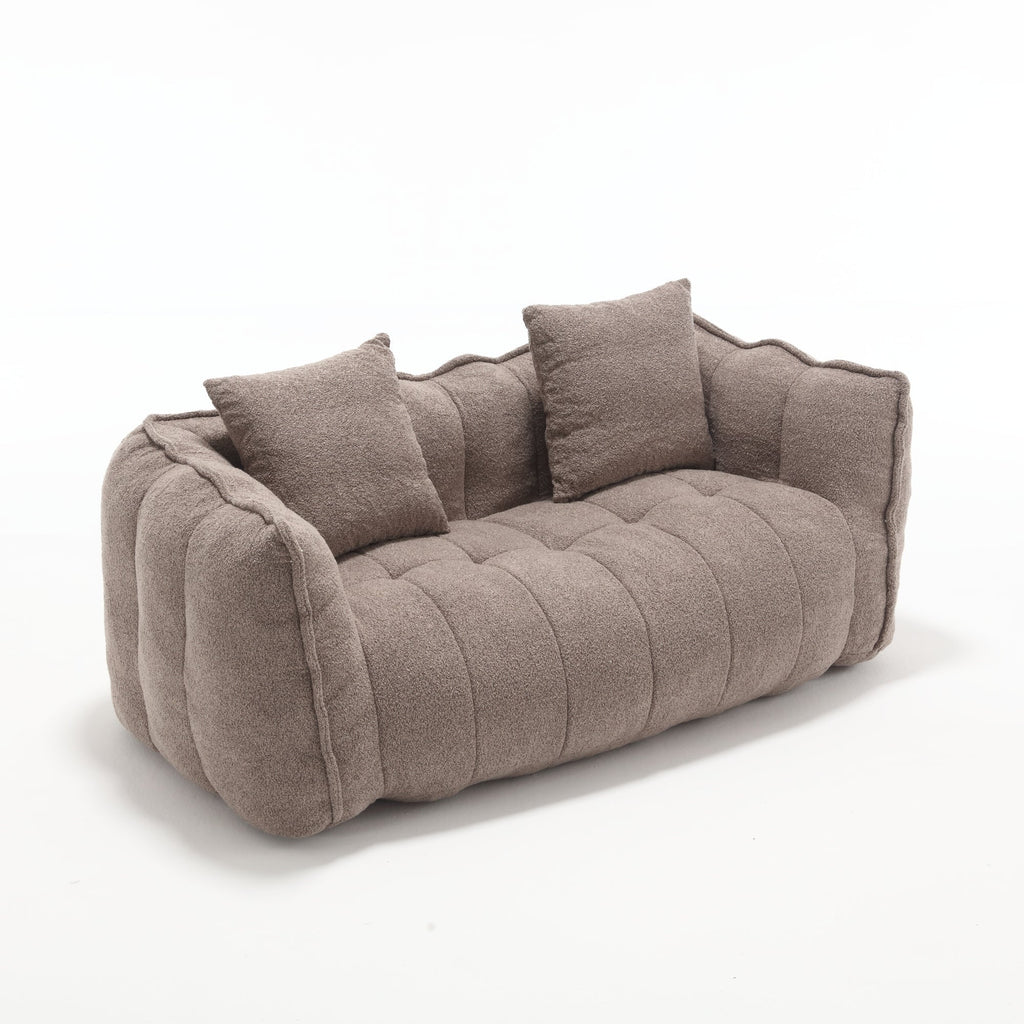 Brown sofa with tufted design and three cushions on a white background