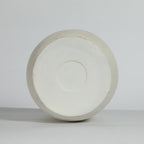 A round, off-white vase bottom from a top-down perspective on a light gray background.