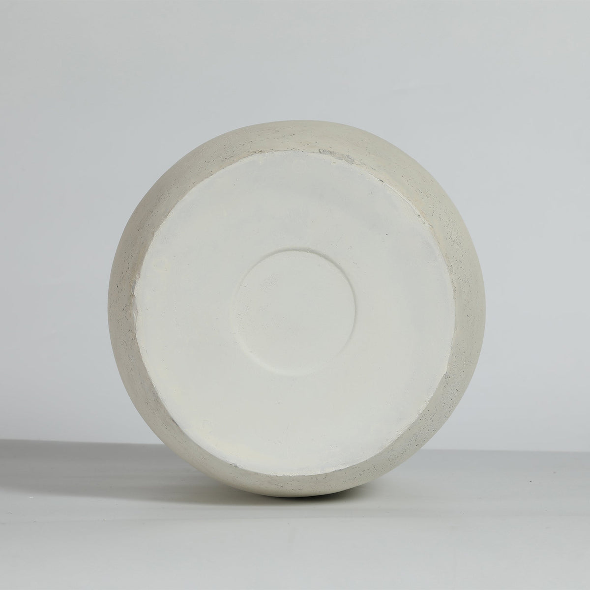 A round, off-white vase bottom from a top-down perspective on a light gray background.