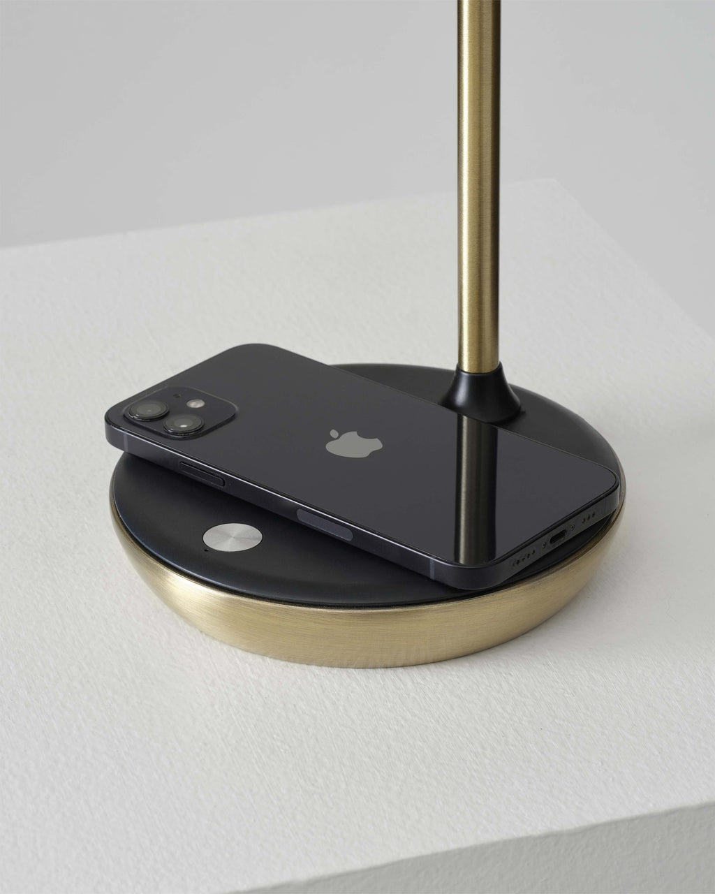 Phone on a lamp stand with a gold base and black platform