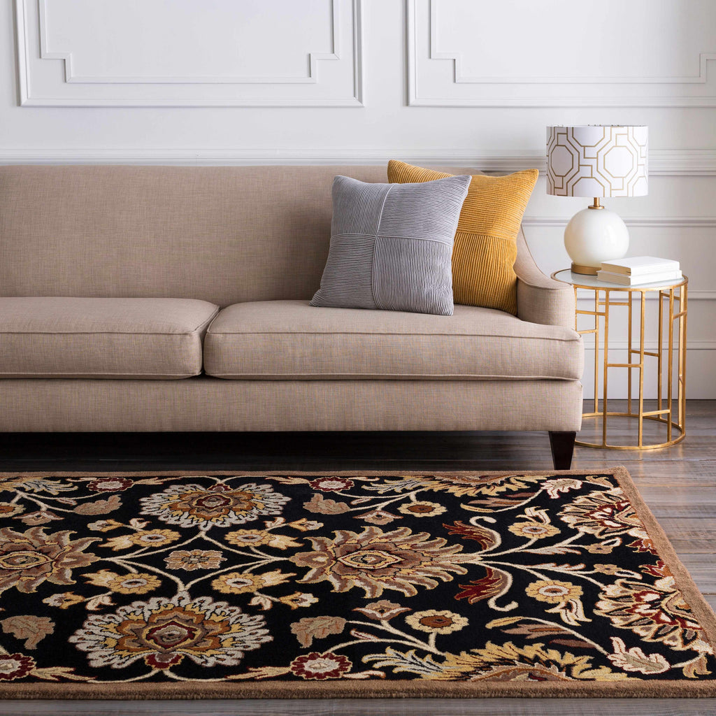 Beige sofa with decorative pillows on a patterned rug in a living room setting.