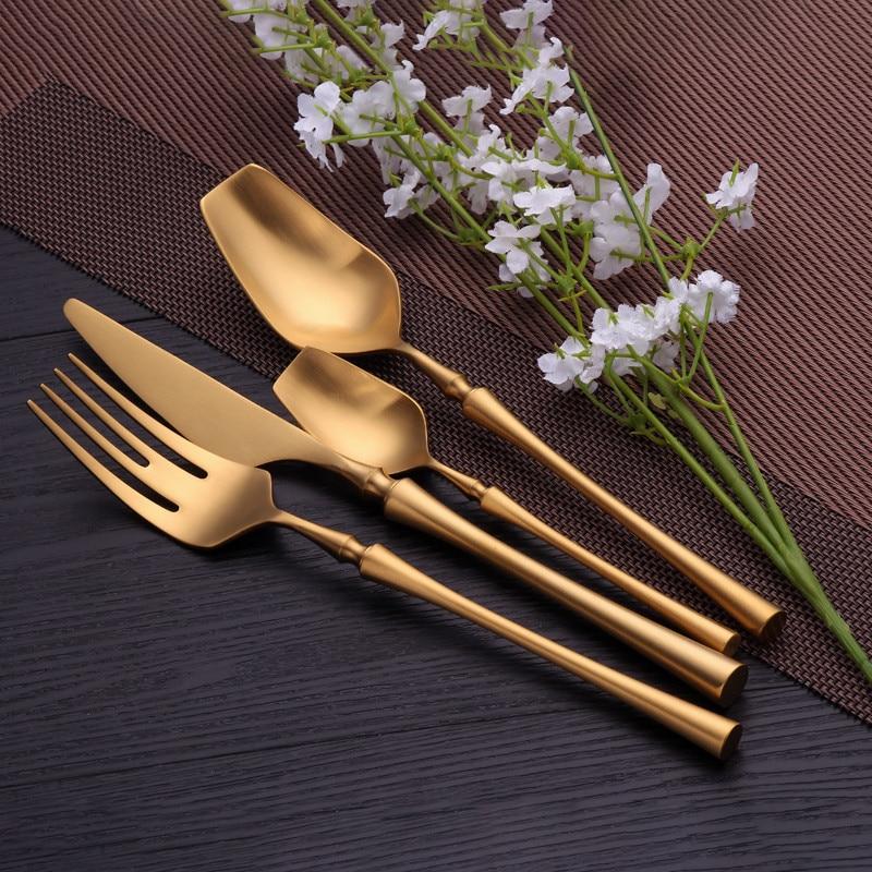 Set of gold cutlery on a dark surface with white flowers.