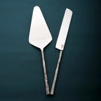 Metal cake server and knife set on a dark green background