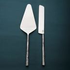 Two metal cake knives on a dark green background