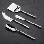 Set of four silver cheese tools on a dark surface
