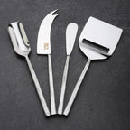 Set of four metal cheese tools on a dark surface