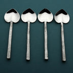 Four silver spoons on a dark green background