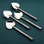 Set of four silver spoons on a dark green background
