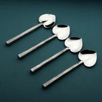 Set of four silver spoons with heart-shaped bowls on a dark green background