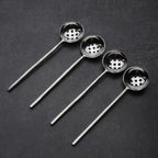 Set of four ladles with perforated bowls on a dark surface
