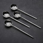Set of four black ladles with perforated ends on a dark surface