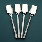 Set of four silver stilton spoons on a dark green background