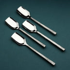 Set of four silver stilton spoons on a dark green background