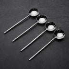 Set of four steel sugar spoons on a dark surface