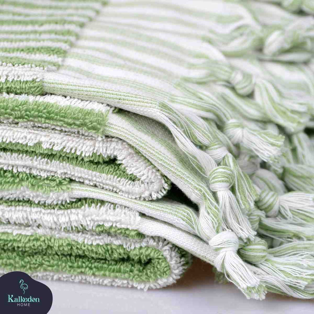 Close-up of lime green and white striped hand towels with fringed edges, stacked neatly.