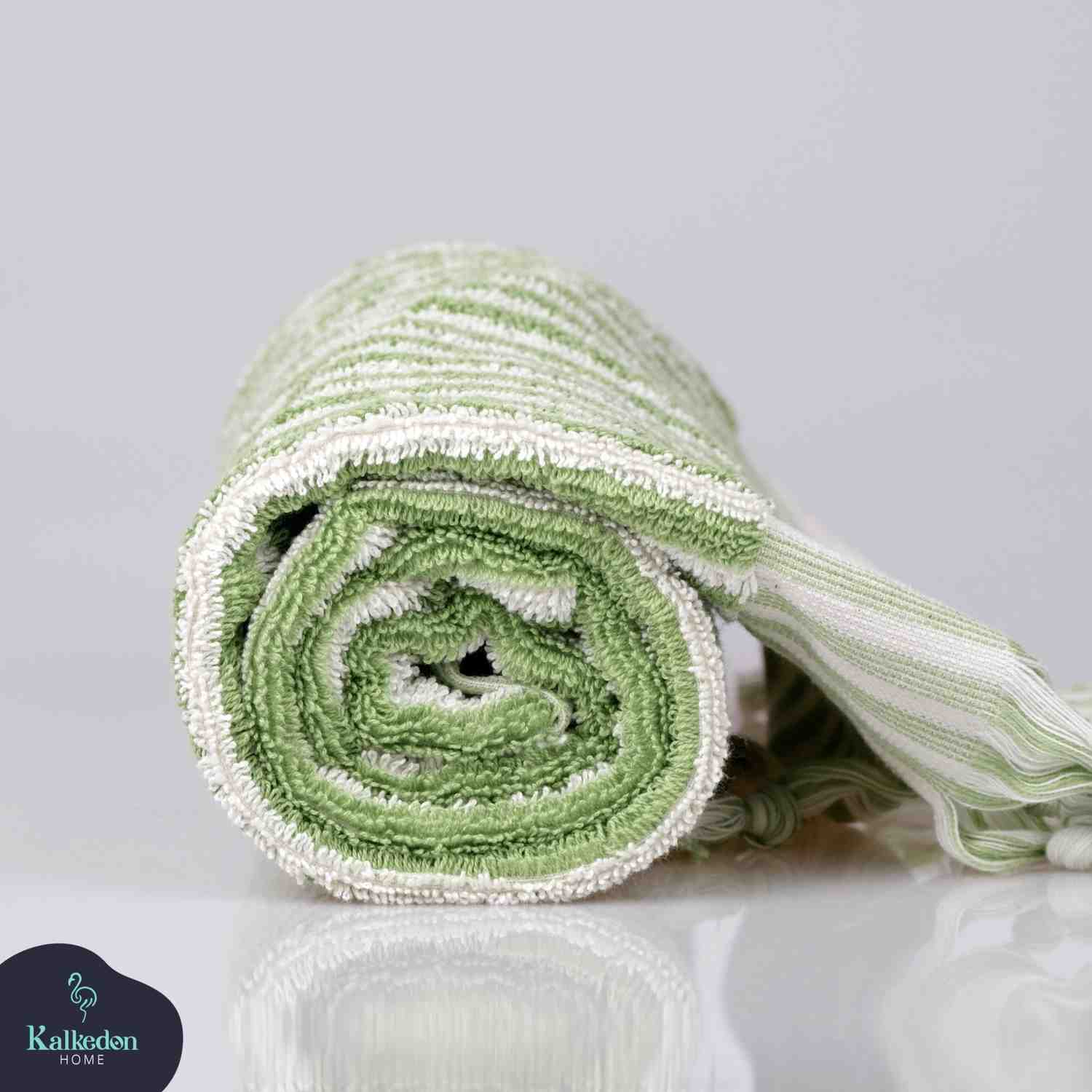 rolled lime green and white striped hand towel with soft texture on a reflective surface