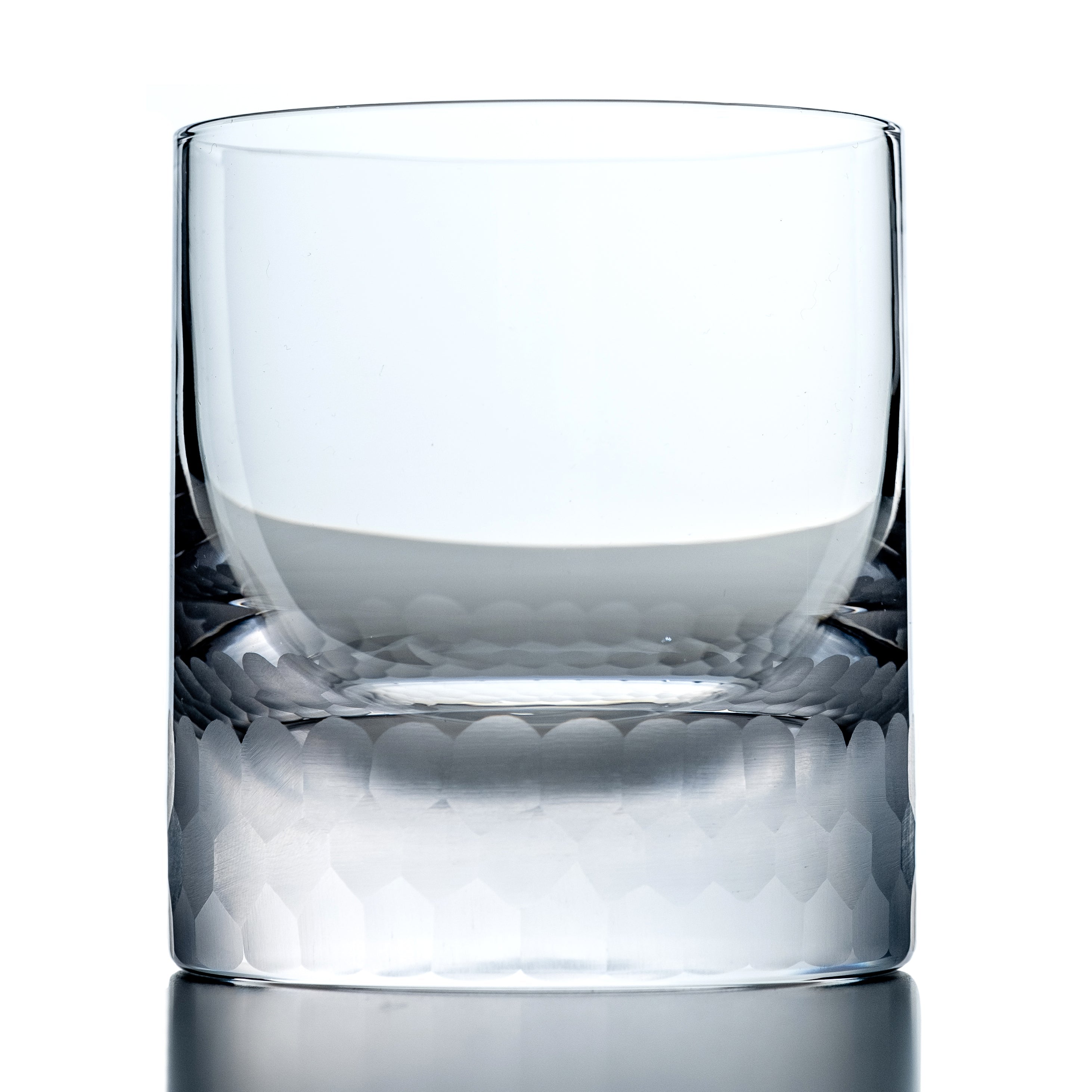 Clear whiskey glass with textured bottom on a white background