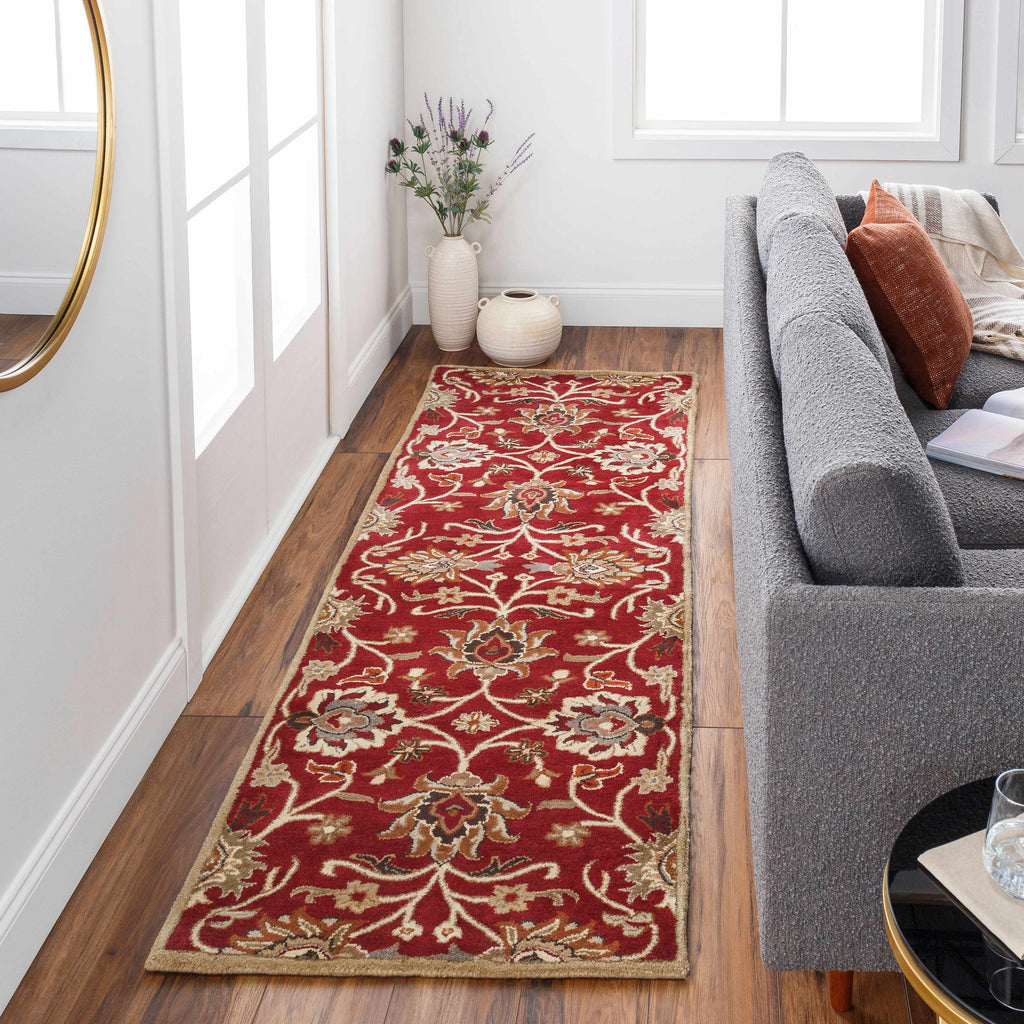 Red patterned rug on a wooden floor in a living room with a gray sofa.