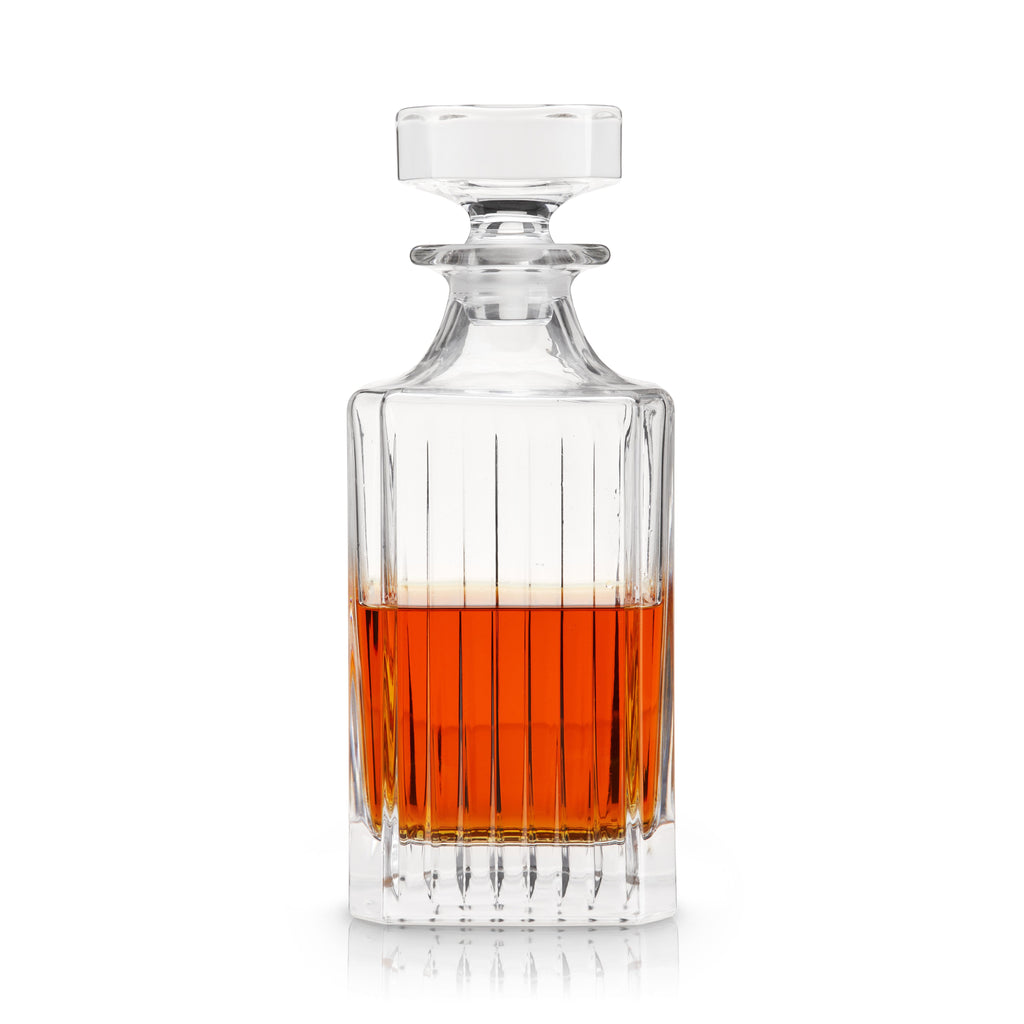 Clear glass decanter with amber liquid on a white background