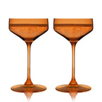 Two amber-colored cocktail glasses on a white background