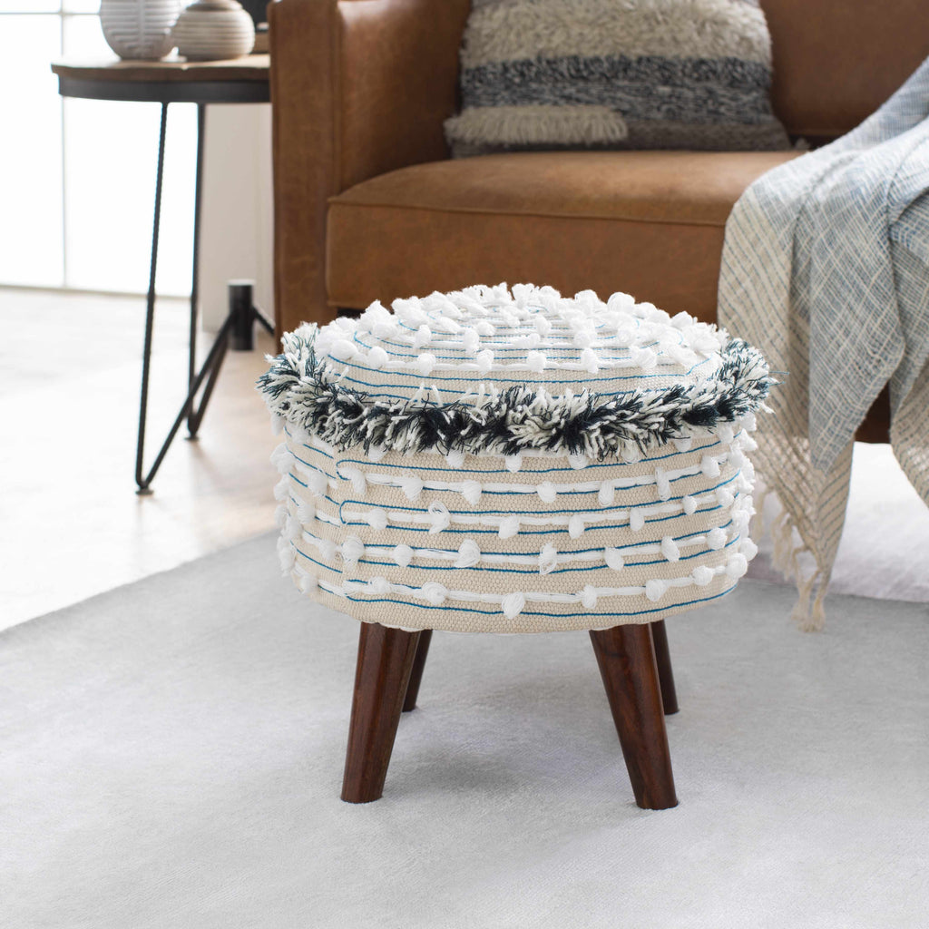 Decorative ottoman with woven top and wooden legs in a living room setting.