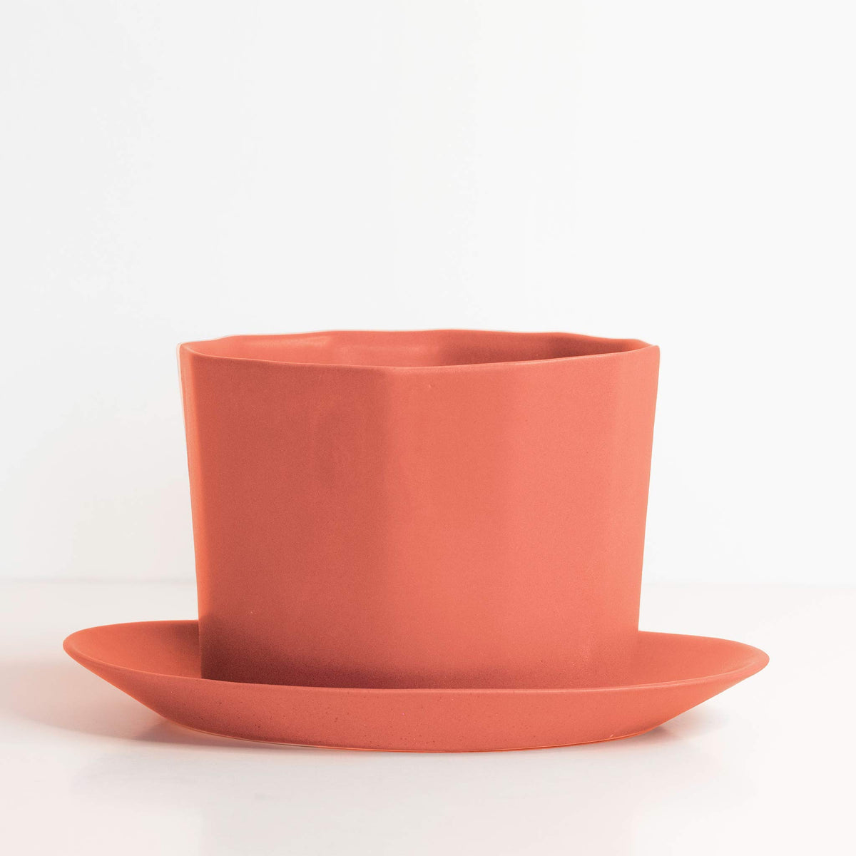 Terracotta-colored planter and saucer set on a white background