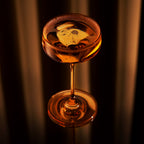 Amber cocktail in a coupe glass against a dark background