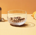 Clear glass bowl with stones on a yellow tiled surface