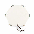 An octagonal white stone serving board with a dark brown leather loop on one side and decorative multicolor inlay at the corners, shown on a white background.