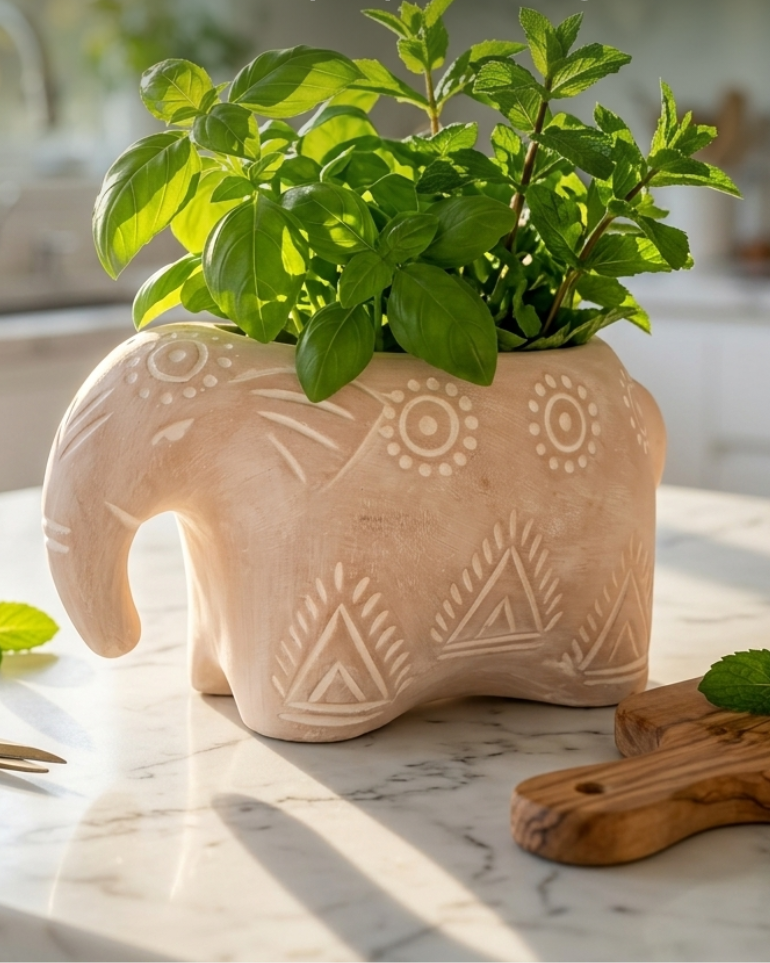 Decorative ceramic elephant planter with green leaves on a kitchen counter.