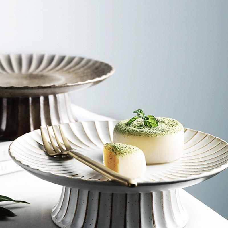 Two small desserts on a decorative cake stand with a light background
