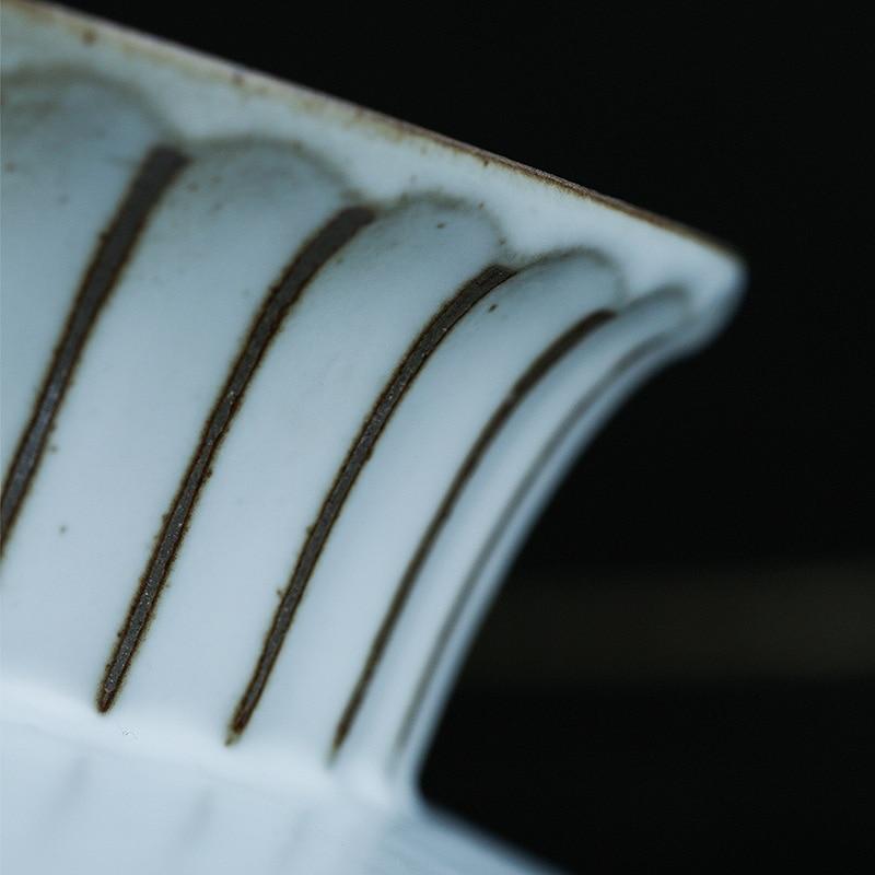 Close-up of a ceramic cake stand with decorative lines on a dark background