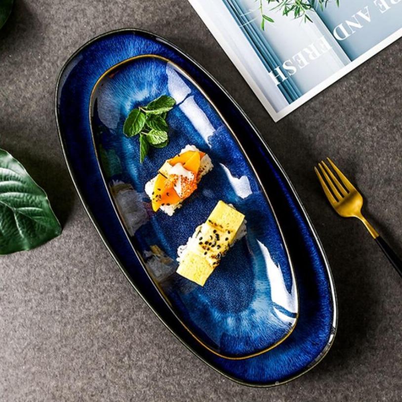 Eye of Ocean glazed ceramic long plate, large — overhead view with sushi pieces on deep cobalt blue reactive glaze with gold rim, gold fork beside