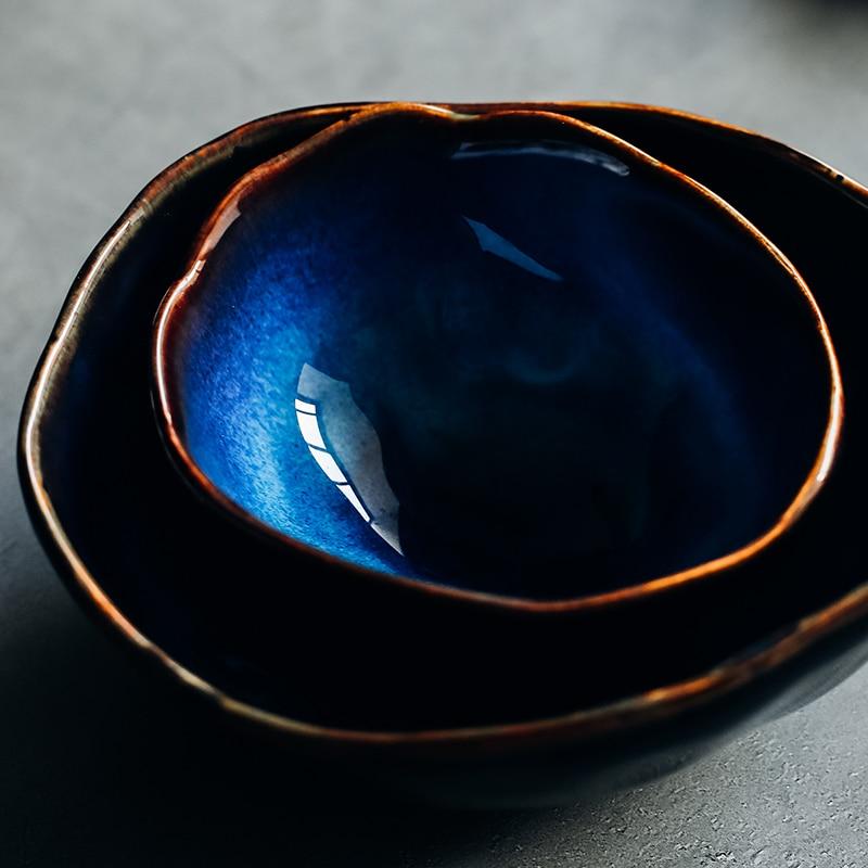 Close-up of two nested Amelia porcelain soup bowls showing deep cobalt blue reactive glaze and organic irregular bronze-fired rim
