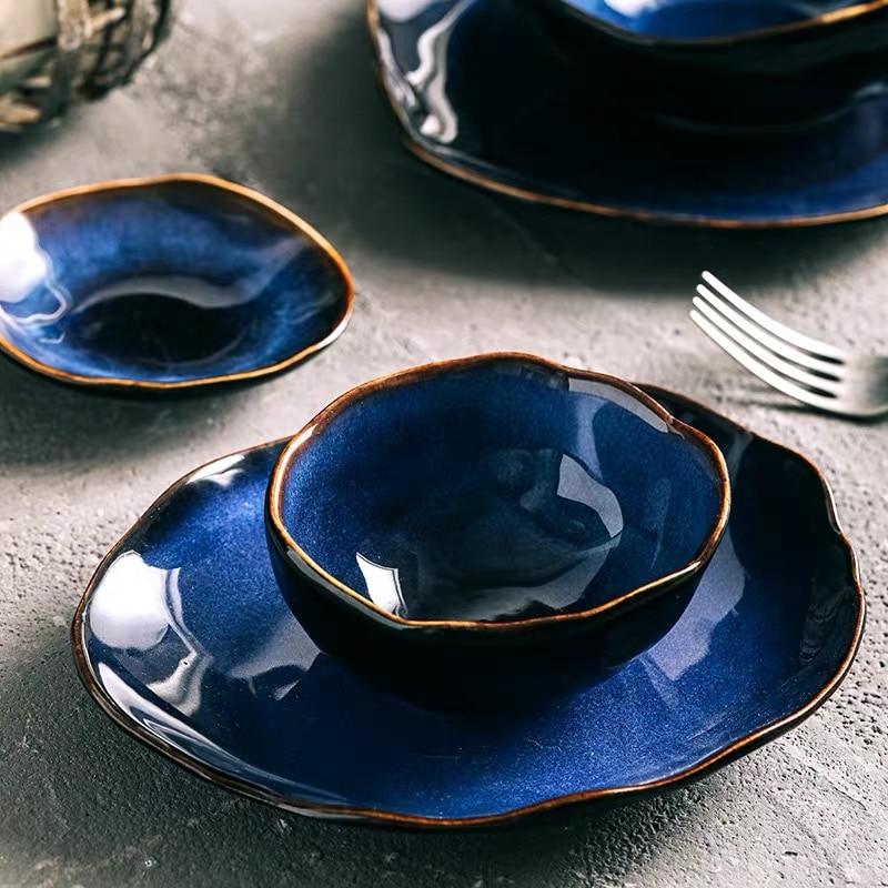 Amelia porcelain dinner plate and bowl place setting with flatware on a slate surface, cobalt blue glaze with organic oval form