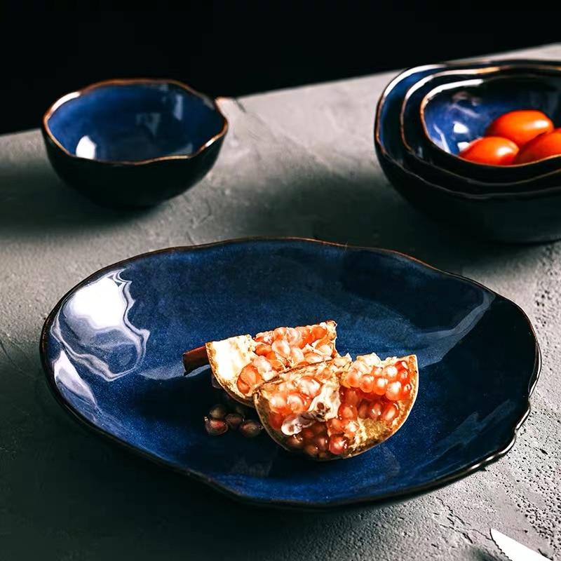 Amelia Blue Porcelain Dinnerware — stacked place setting with oval dinner plate, soup bowl, and dessert plate in cobalt blue glaze with bronze rim